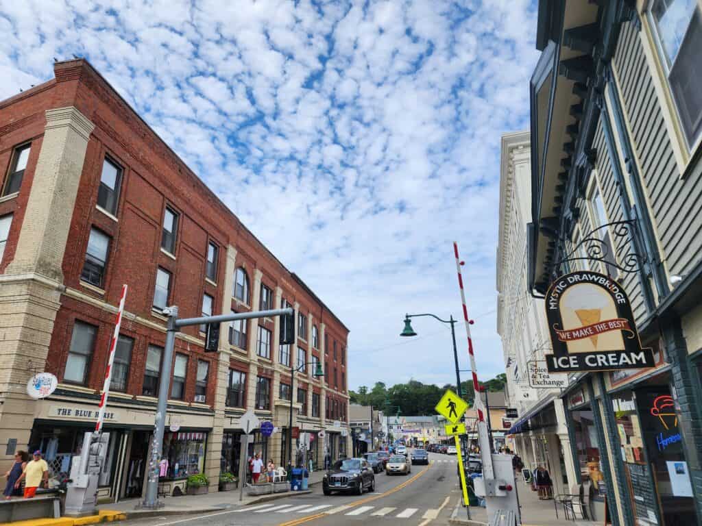 exploring the downtown is one of the best things to do in mystic CT: this image shows a street lined with shops on a clear summer day
