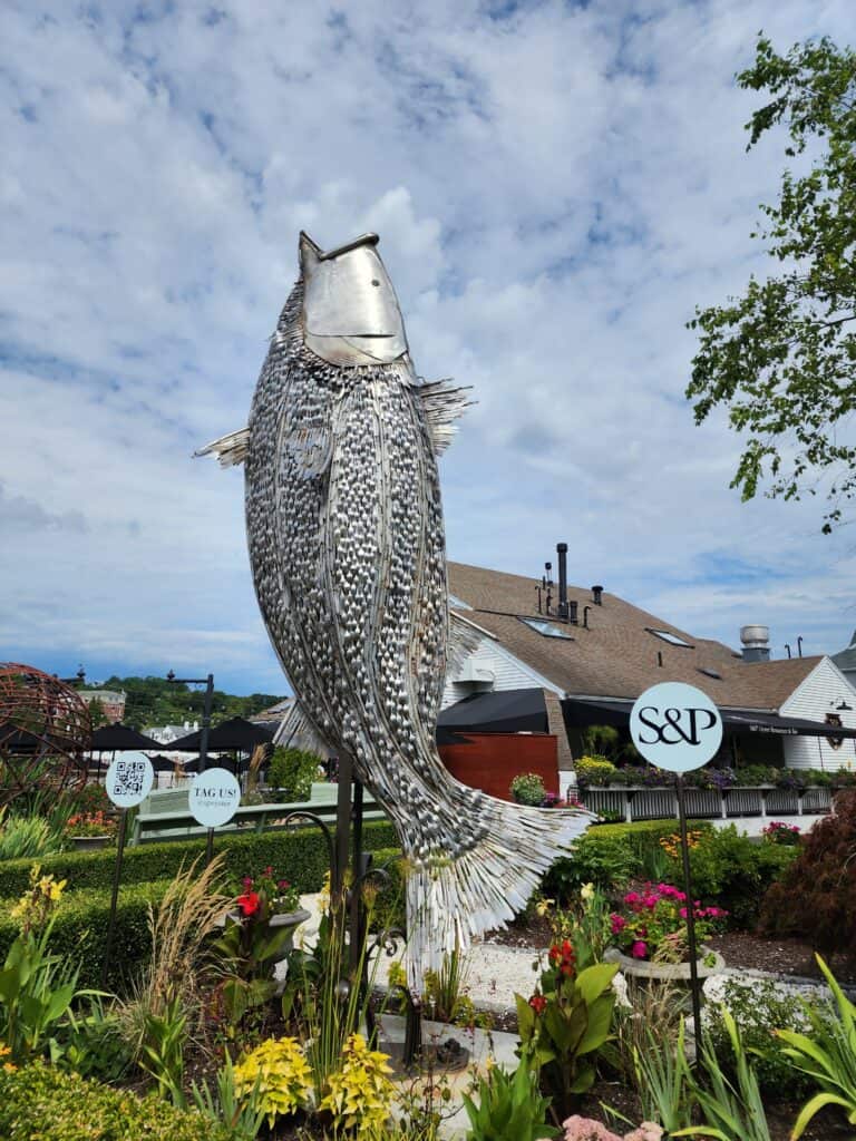 a large metal sculpture of a fish, outside S & P Oyster restaurant in mystic connecticut