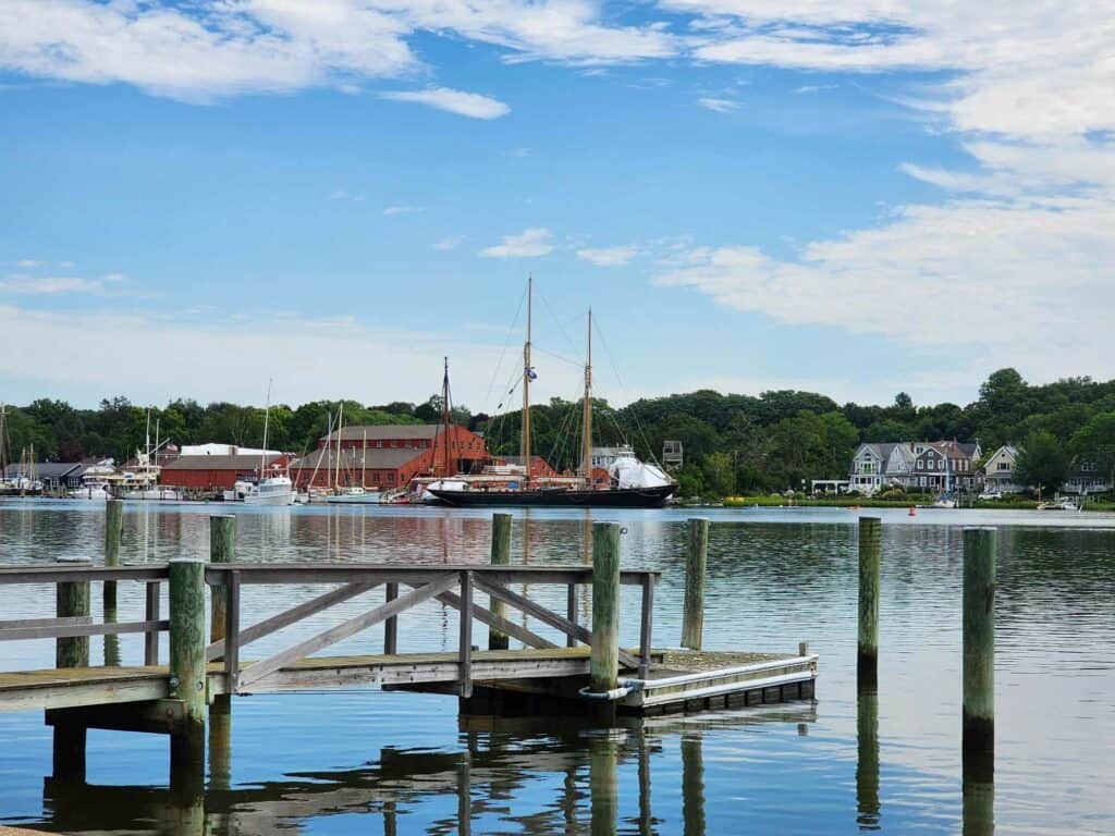 a tall saling ship seen across a river from a dock, mystic CT