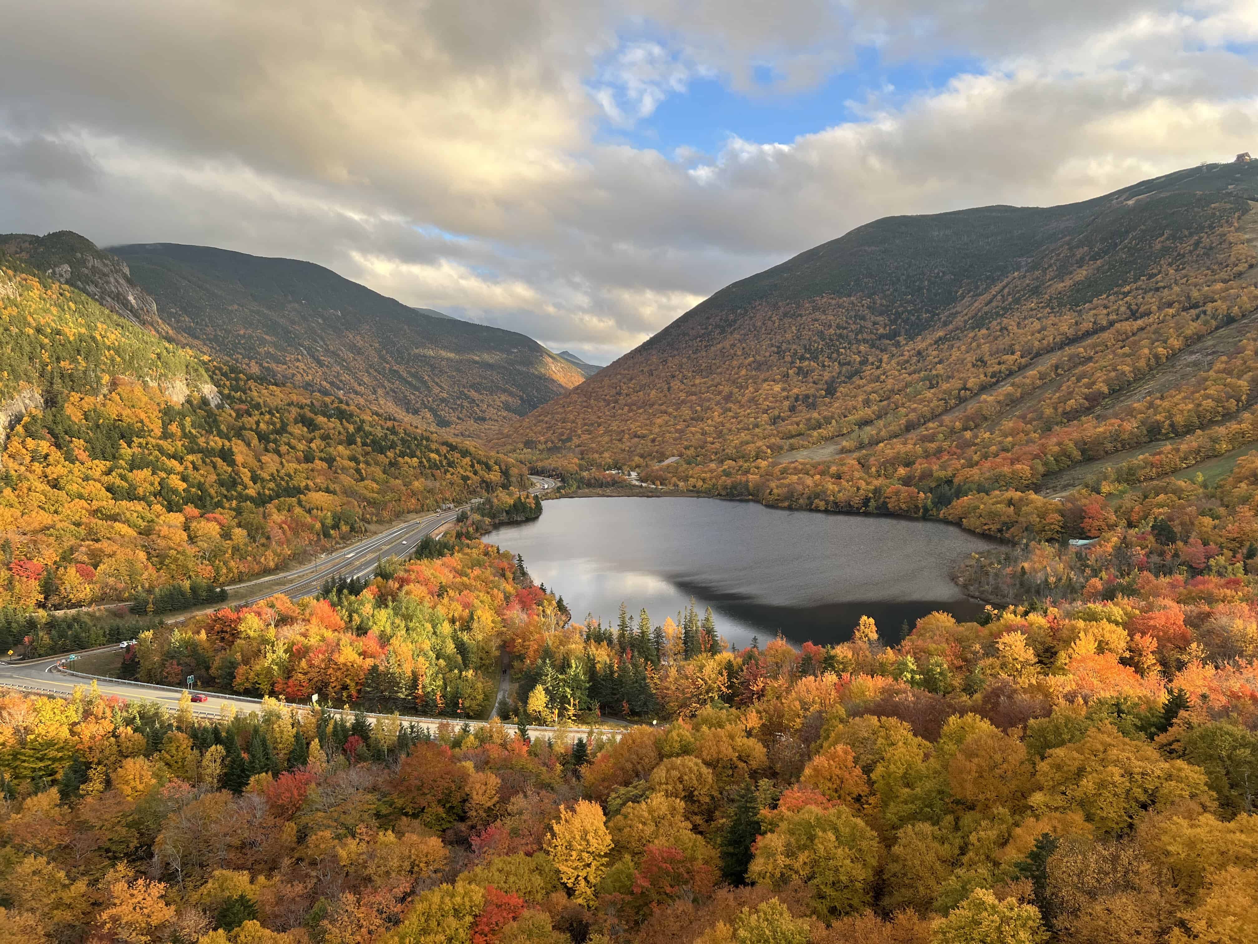 a gorgeous fall scene, a still lake surrounded by fall colored mountains in new hampshire