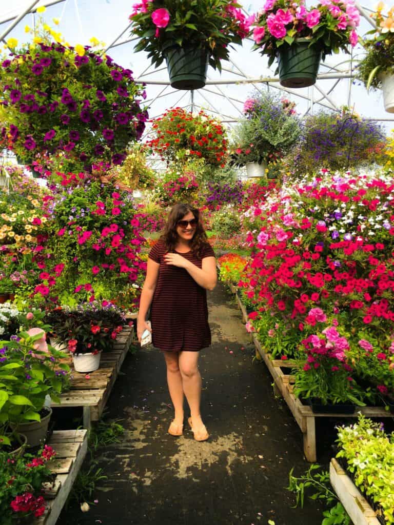 amy standing in a greenhouse filled with flowers