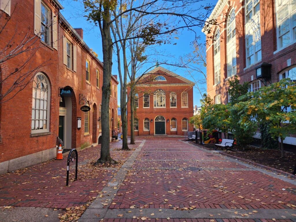 Salem old town hall - a colonial style brick building at the end of an empty brick walkway strewn with fallen leaves