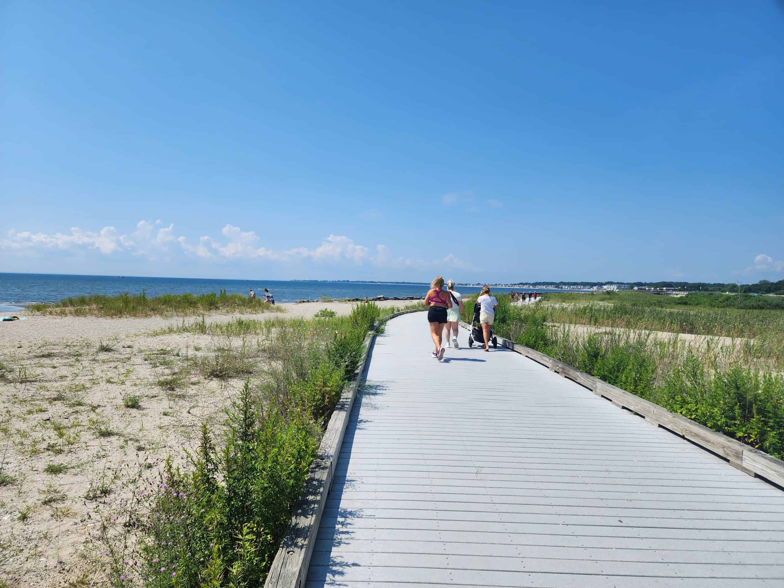 a beachside boardwalk with runners on it and the sea beyond, silver sands state park, milford CT