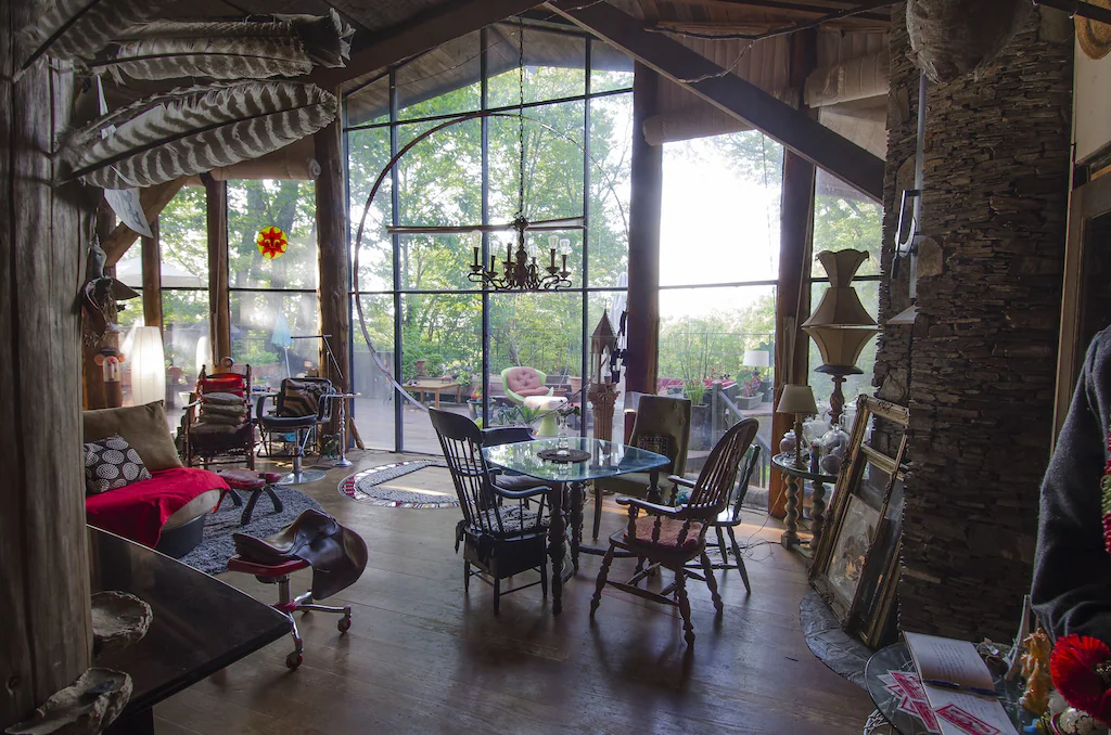 A table and chairs sit by a wall of windows and a stone fireplace