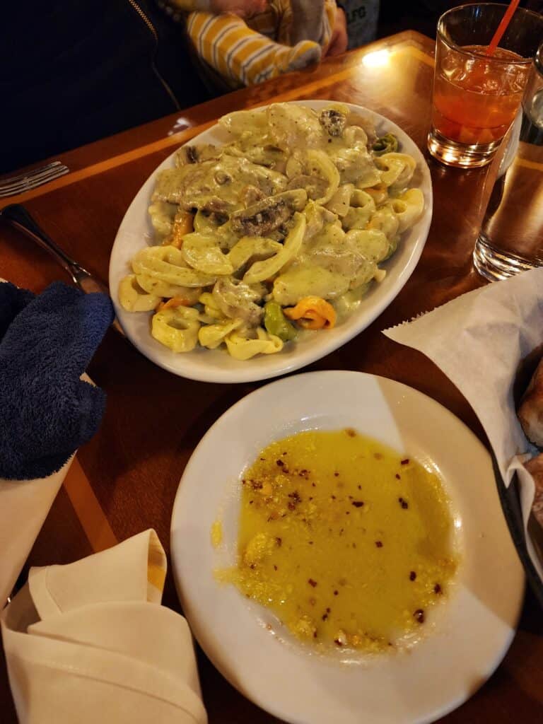 a photo of food on plates, one dish is tri color tortellini, the other is oil and garlic on a plate, a delicious italian restaurant