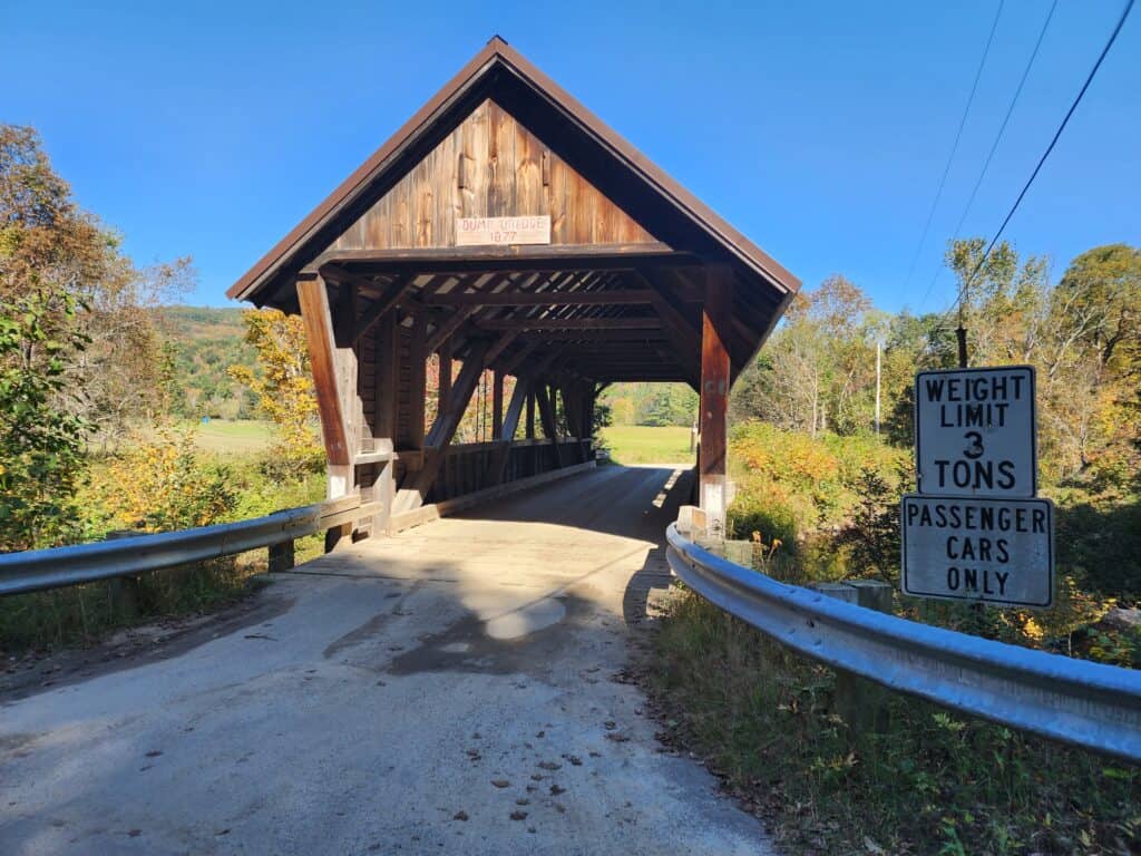 a simple wooden covered bridge at the end of a country lane, new hampshire
