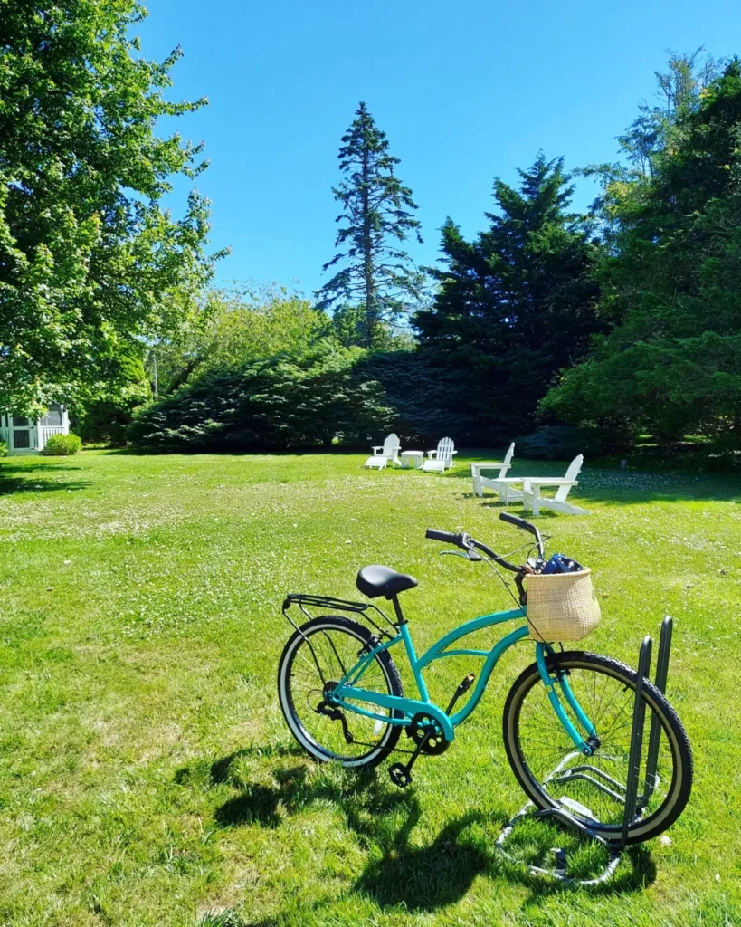 A bike on a grassy lawn with white lawn chairs on Cape Cod
