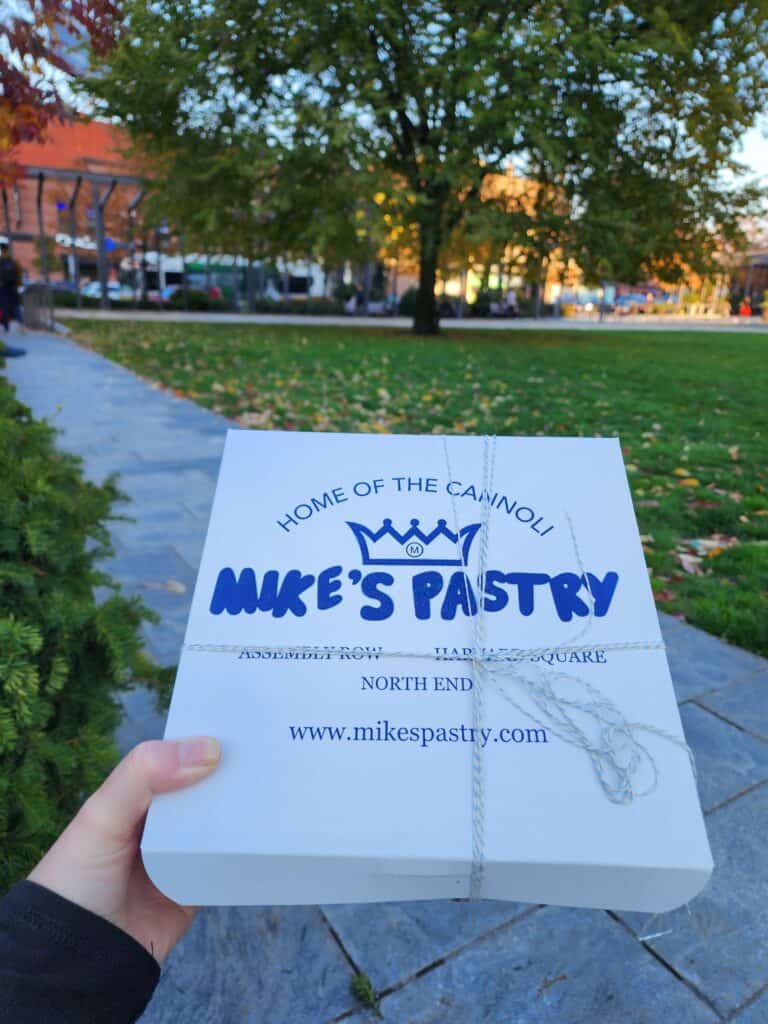 A white Mike's Pastry box as seen in a Boston park