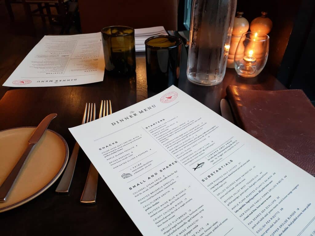 a menu on a dinner table with small candles nearby