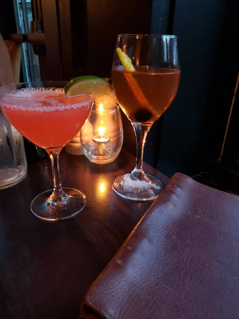 a cocktail and a glass of wine on a table