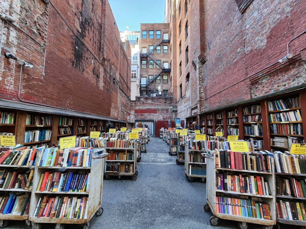 a brick walled alley filled with rows of books on shelves, brattle book shop in boston ma