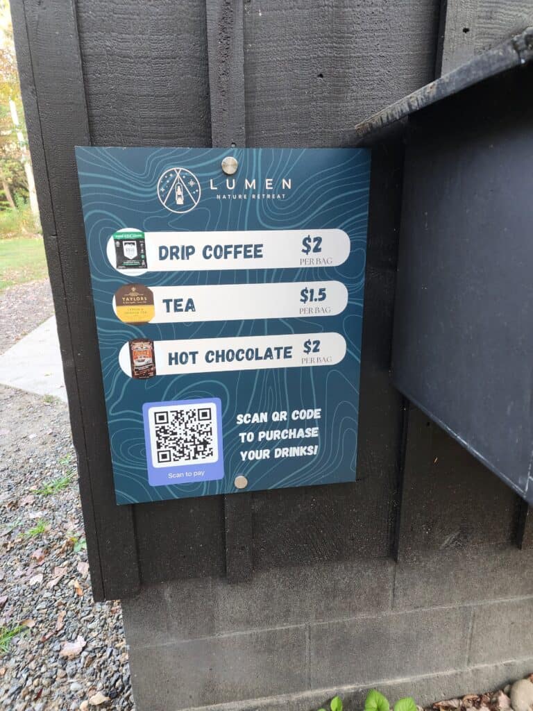 a sign advertising coffee, tea, and hot chocolate for sale, and featuring a scannable QR code for people to pay via mobile