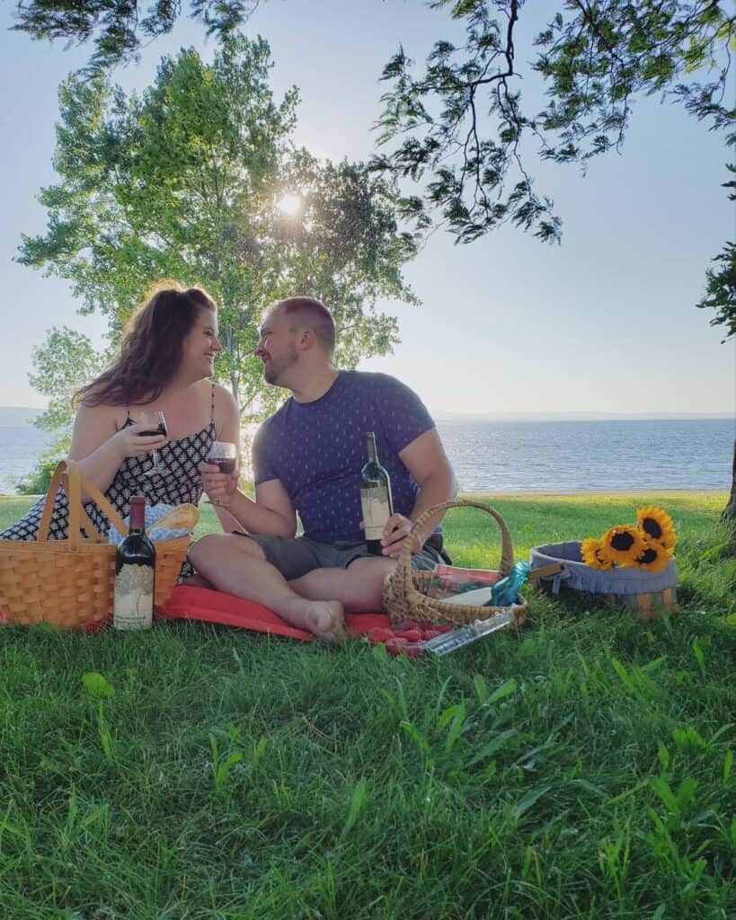 a man and woman enjoying a summer picnic on lake champlain, Vermont, with flowers and wine