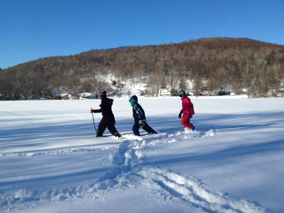 3 young people trekking through deep snow on a sunday vermont day