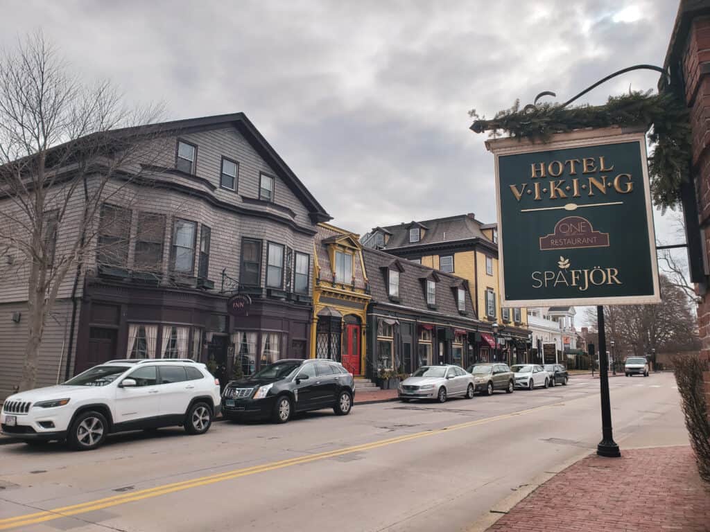 newport rhode island is one of the best day trips from new england - this image shows historic buildings lining a street with cars parked along the road