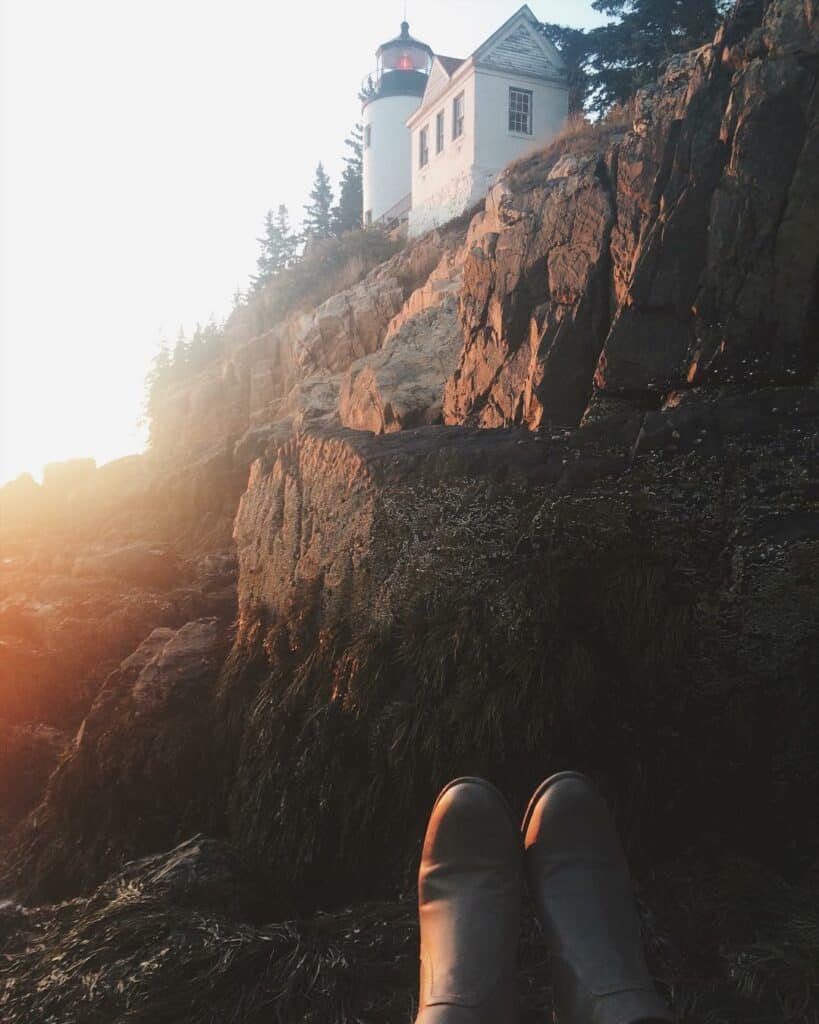 A woman's shoes at the bottom of the frame of the Bass Harbor Lighthouse in Acadia National Park