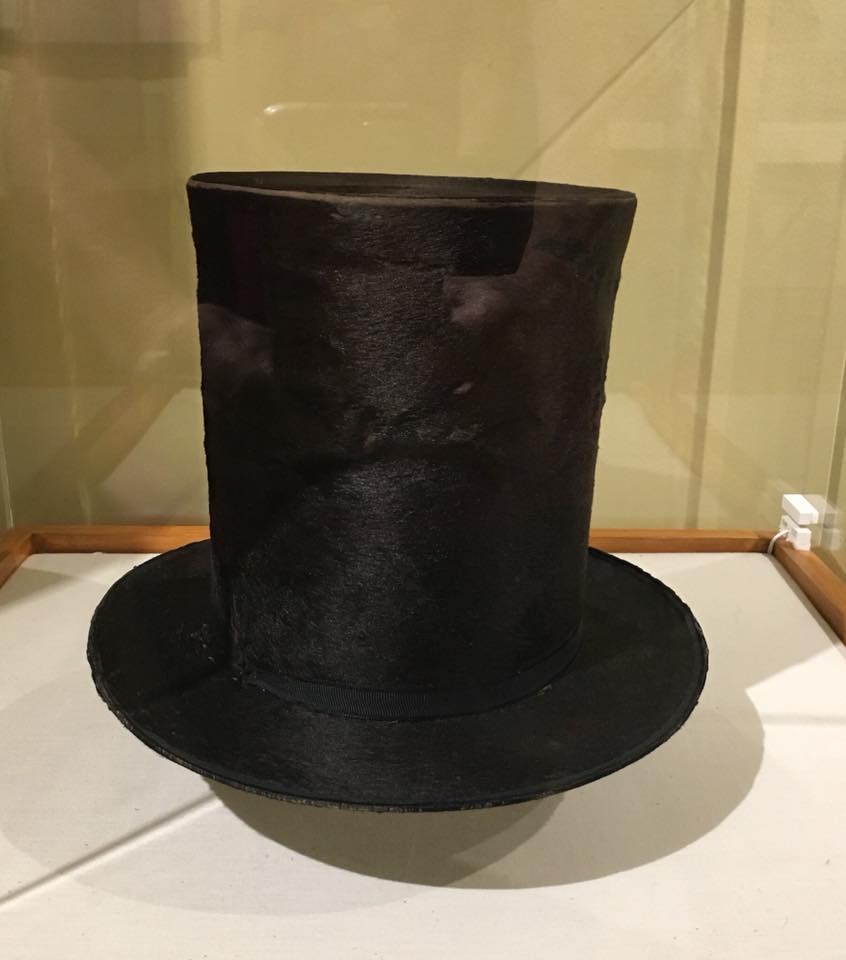 a black top hat in a glass case
