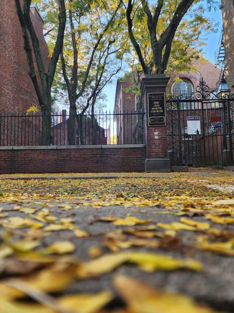 Ground-level view of fallen yellow leaves paving the way to the historic Old North Church in Boston, a quintessential sight in the array of things to see in Boston 