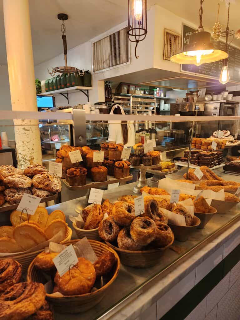 An assortment of freshly baked pastries on display at a Boston bakery, with a warm, inviting atmosphere highlighted by soft lighting and rustic decor.