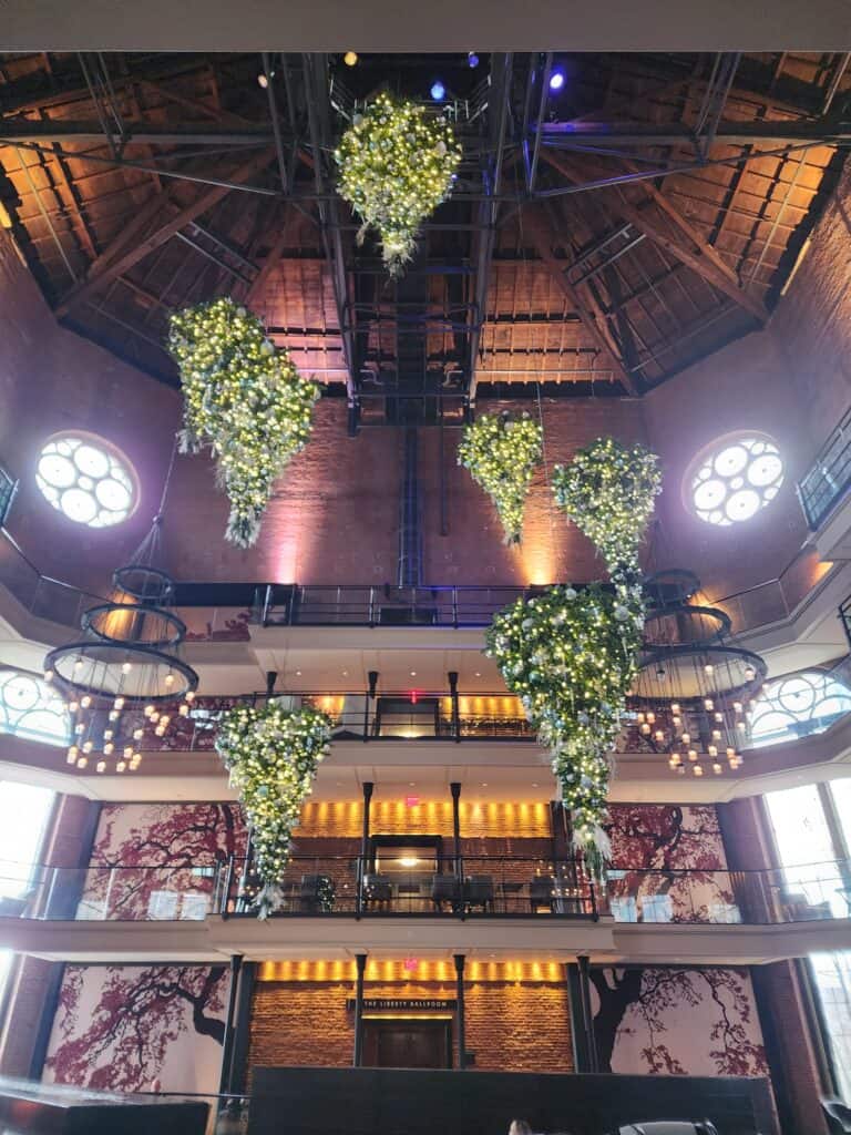 A view of the Liberty Hotel in Boston, featuring a dramatic atrium with cascading greenery and flowers, accentuated by warm lighting and the hotel's unique blend of historic and modern design elements