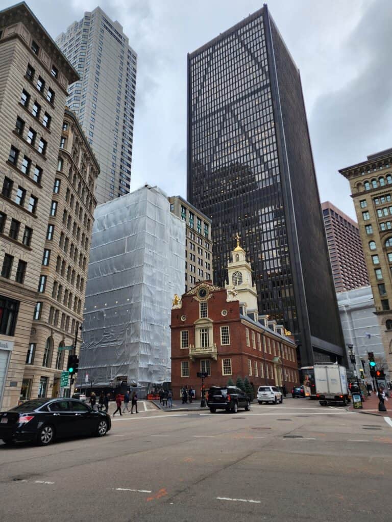 The Old State House, a historic Boston site, stands prominently among modern skyscrapers under an overcast sky, offering a stark contrast between colonial and contemporary architecture