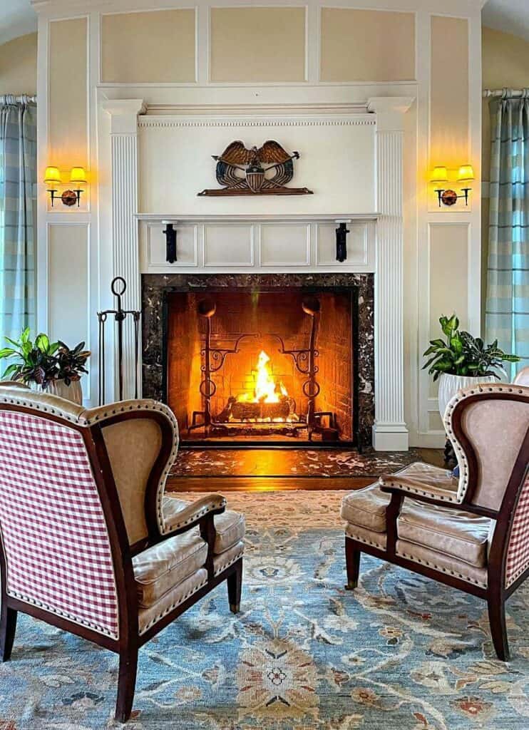 GPT
A cozy room with a classic fireplace burning brightly, flanked by two elegant armchairs upholstered in beige leather with red gingham accents. The fireplace mantle is adorned with a decorative wall art piece, and sconces add a warm glow to the tranquil setting. The room is completed with a patterned blue and beige area rug, creating a welcoming and traditional ambiance.