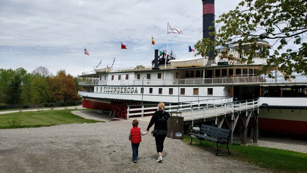 Mother and child walking towards the historic Ticonderoga steamship on display in Vermont, illustrating a family-friendly activity and the state's rich maritime history