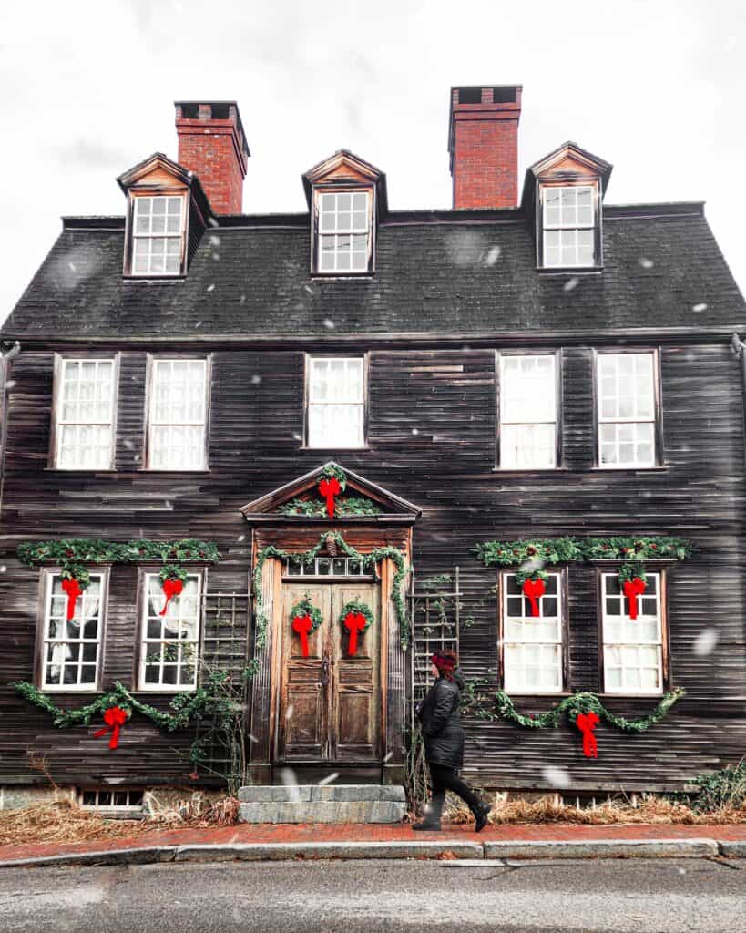 A woman walks in front of a historic New England house decorated for Christmas in Portsmouth, New Hampshire