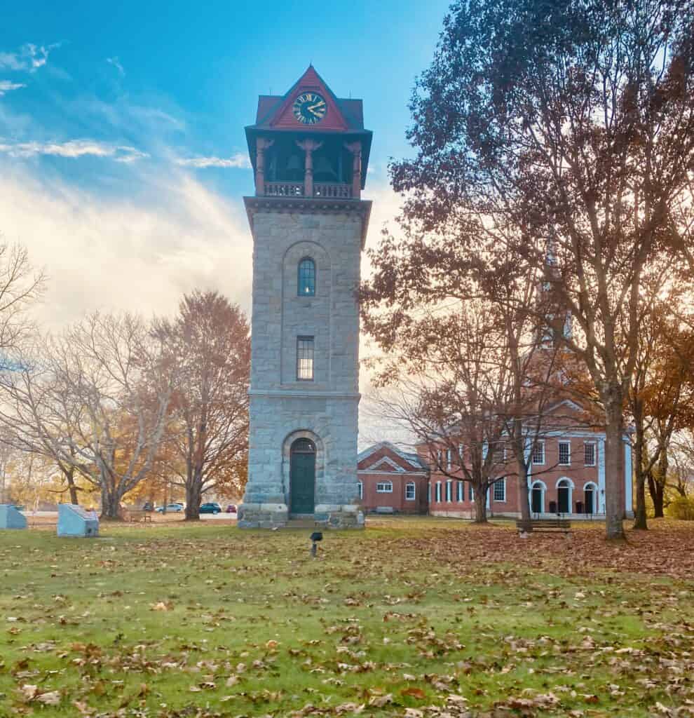 A tall stone clock tower near a church in the Berkshires of Massachusetts