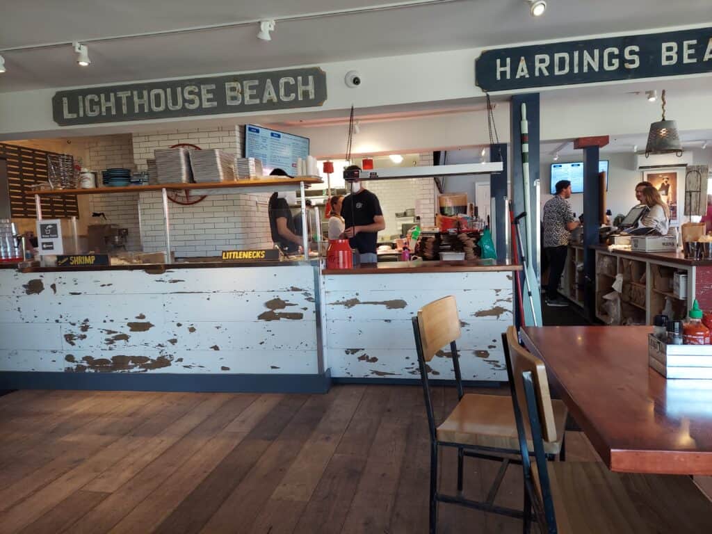 The interior of a seafood restaurant in Chatham, Massachusetts with people working behind the counter as sunlight pours in through the windows