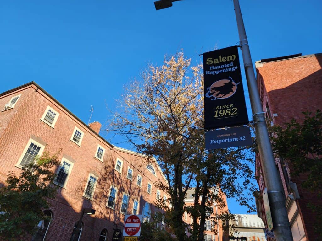 A Salem Haunted Happenings flag is attached to a street light in a historic MA town