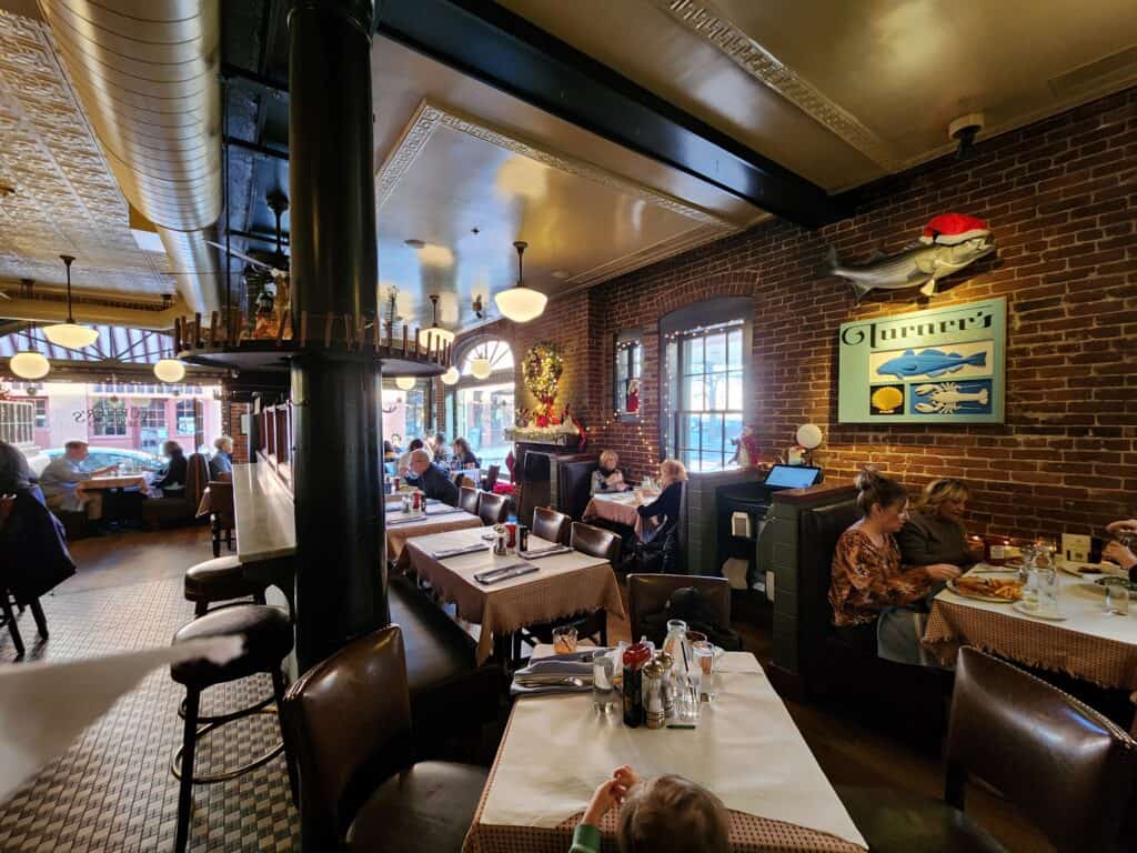A historic Salem MA restaurant with exposed brick walls and antique flooring and people in booths